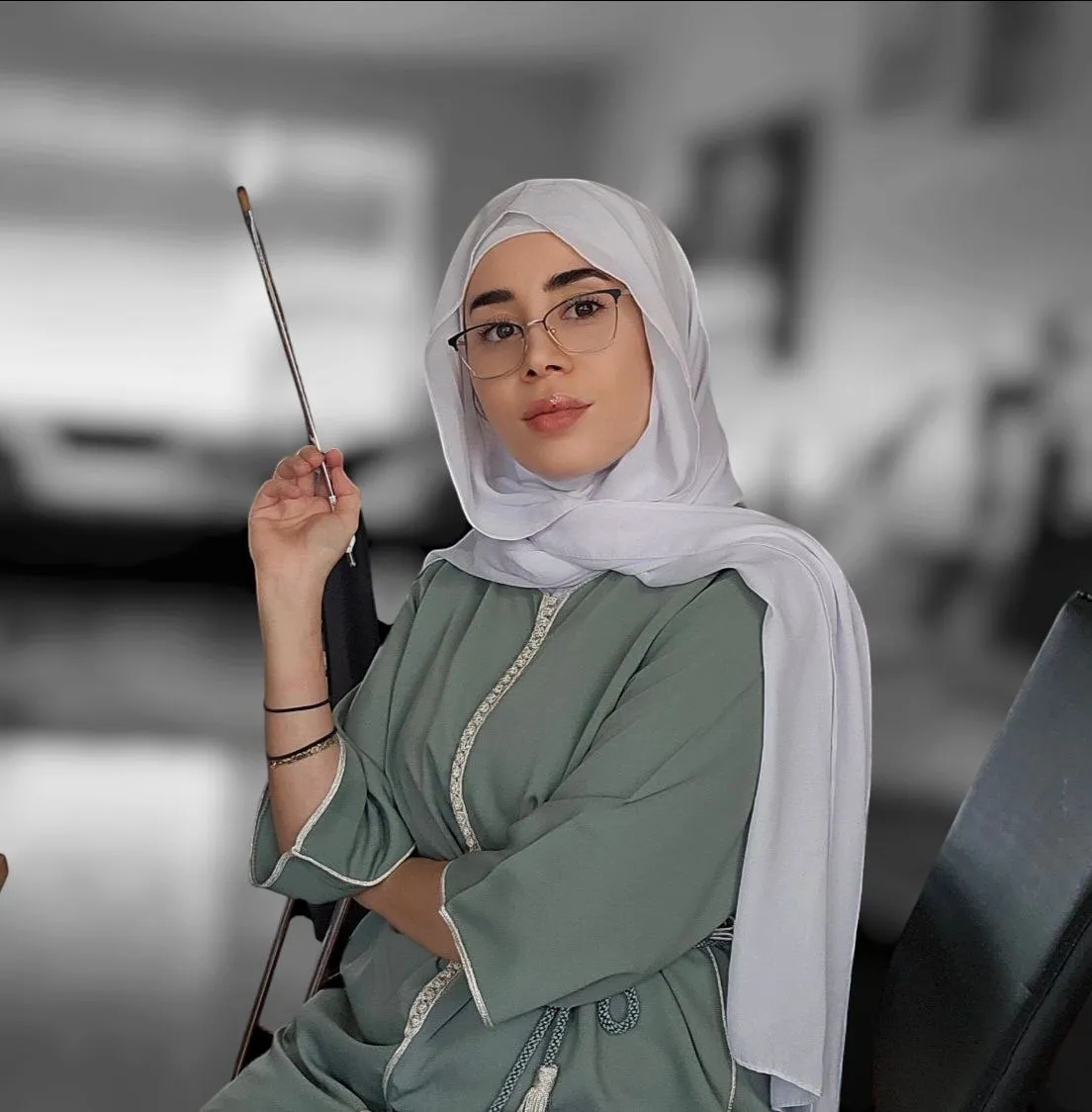 Tima holding a paintbrush in her studio